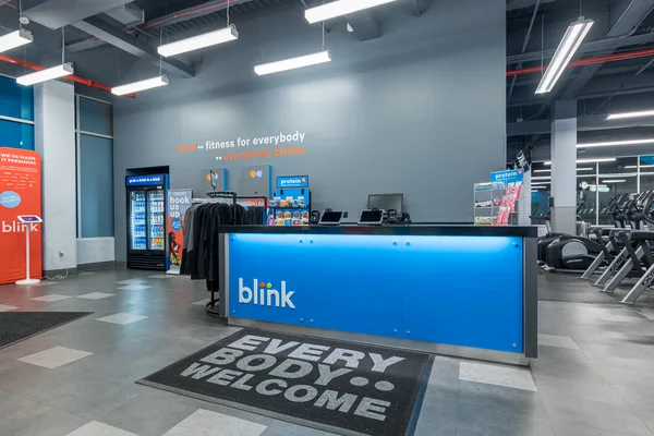 Cardio row of treadmills along a Blink Fitness floor