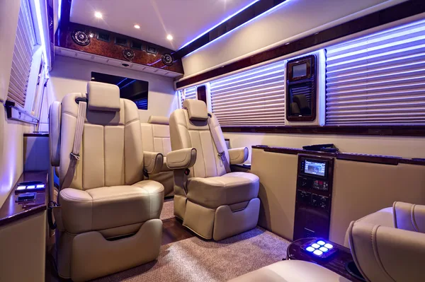 Executive captain's chairs and media screens inside the converted Sprinter