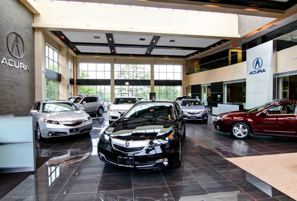 Dealership showroom with a line of sedans angled toward the glass frontage