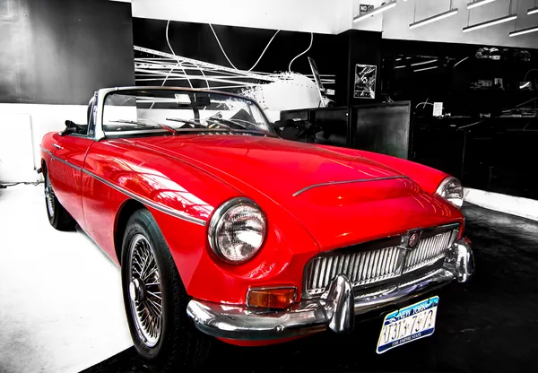 Luxury vehicle photographed on the showroom floor between brand displays